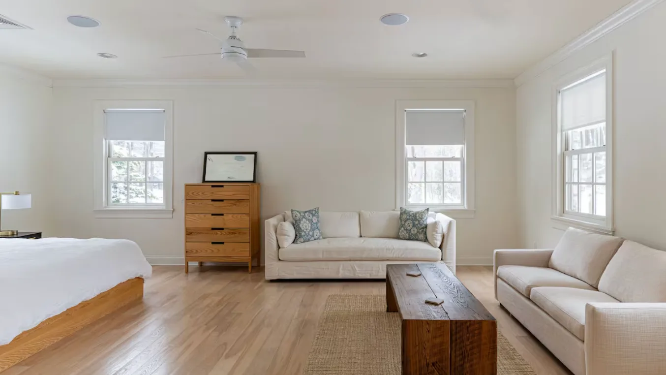 A bright living room with seating, a coffee table, and several windows.