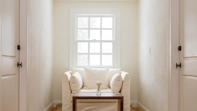 A bright sitting area has cushioned seating beneath a large window.