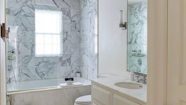 A bathroom with a bathtub and a vanity beside a window.