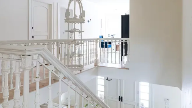 A bright interior landing with a white staircase and decorative railing.