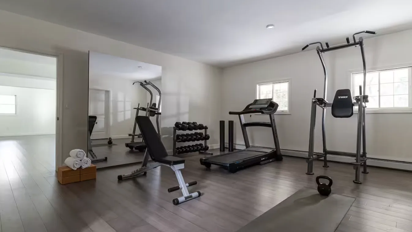 A home gym with exercise machines, free weights, and a kettlebell.