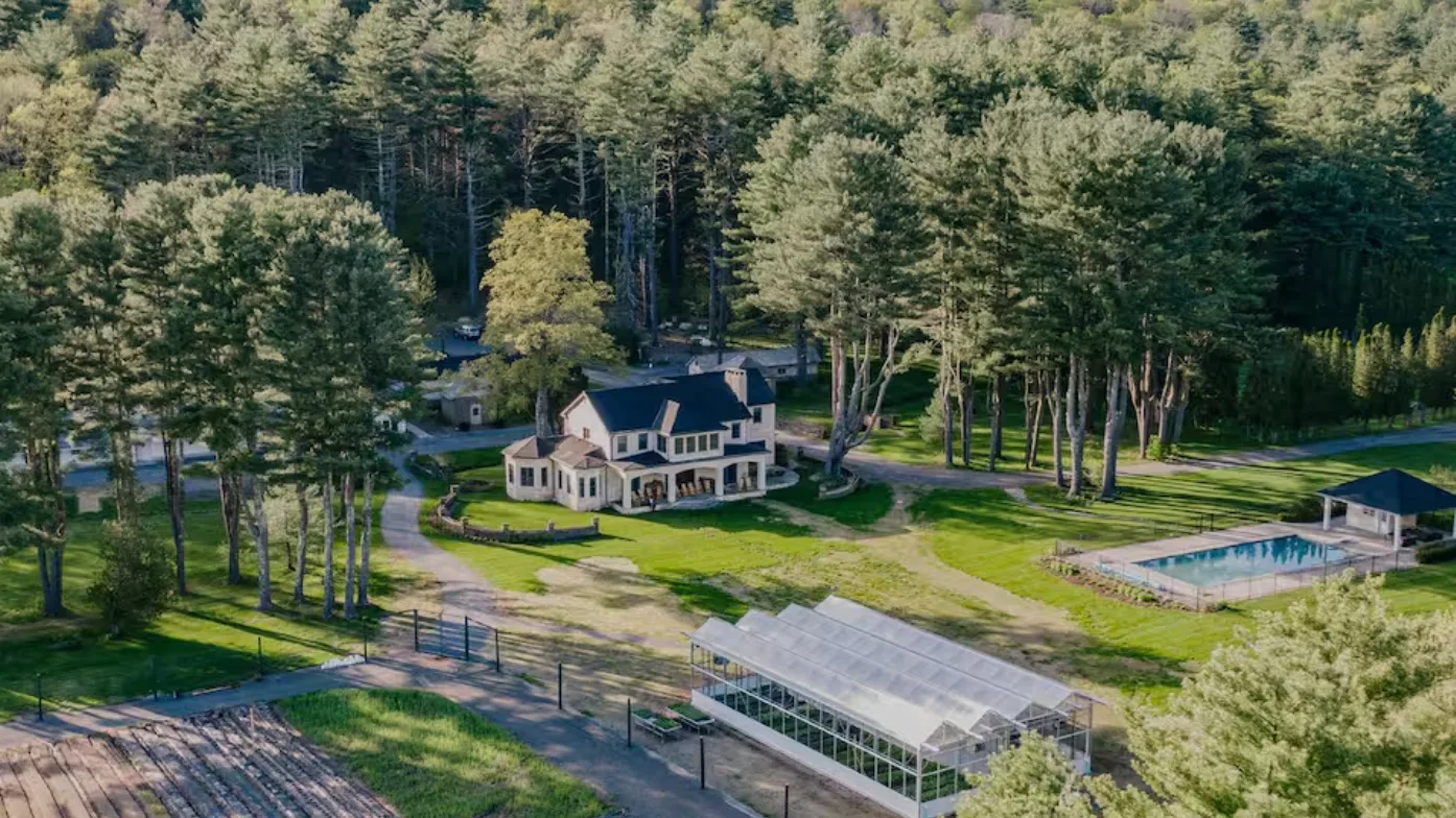 Aerial view of a house and surrounding grounds among tall trees.