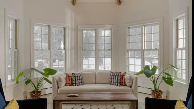 A bright sitting room with a curved sofa and large windows.