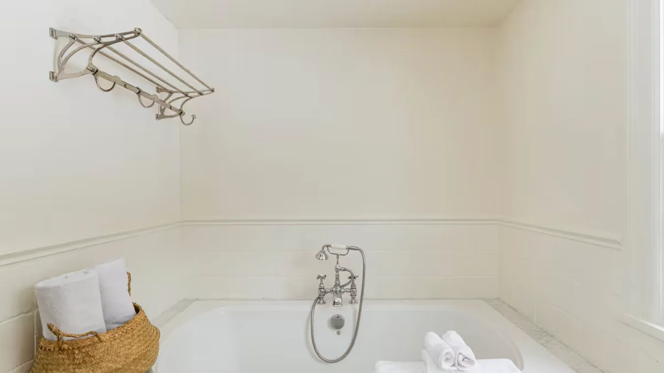 A bathroom with a bathtub and wall-mounted shower fixture.