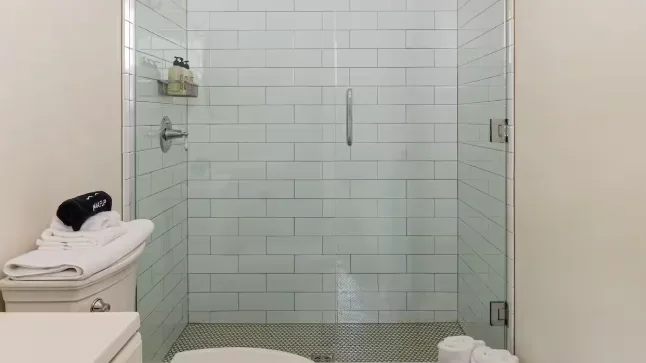 A tiled shower with a folded stack of towels beside it.