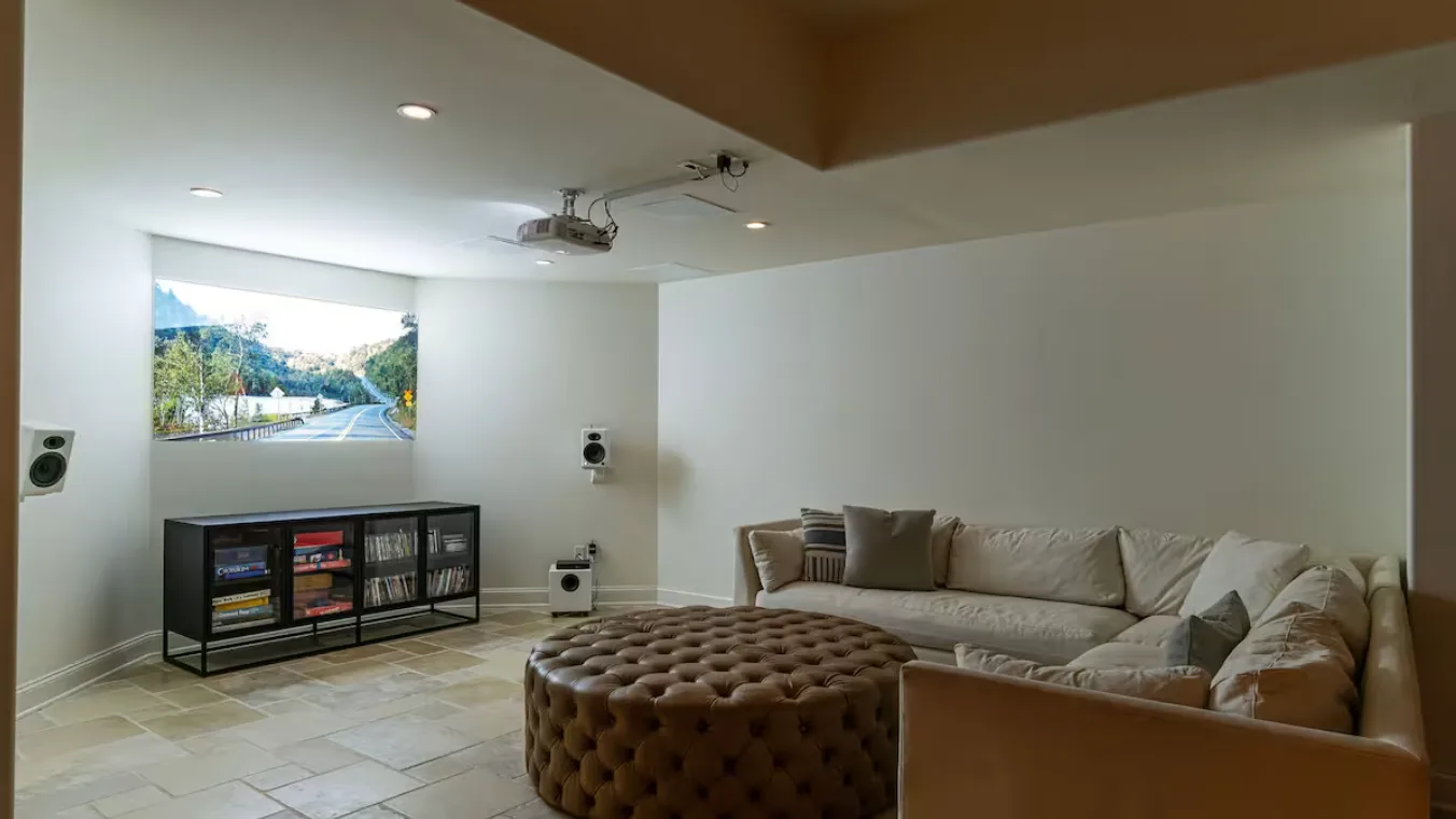 A living room with seating, a round ottoman, and a low media cabinet.