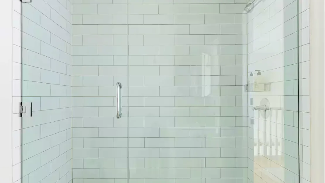 A tiled shower with a glass enclosure and wall-mounted showerhead.