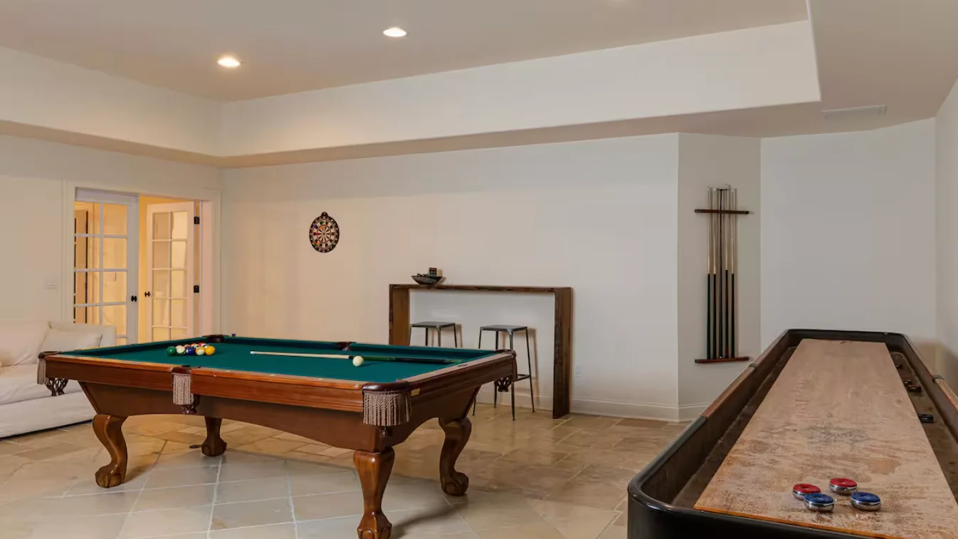A recreation room features a pool table and a shuffleboard table.