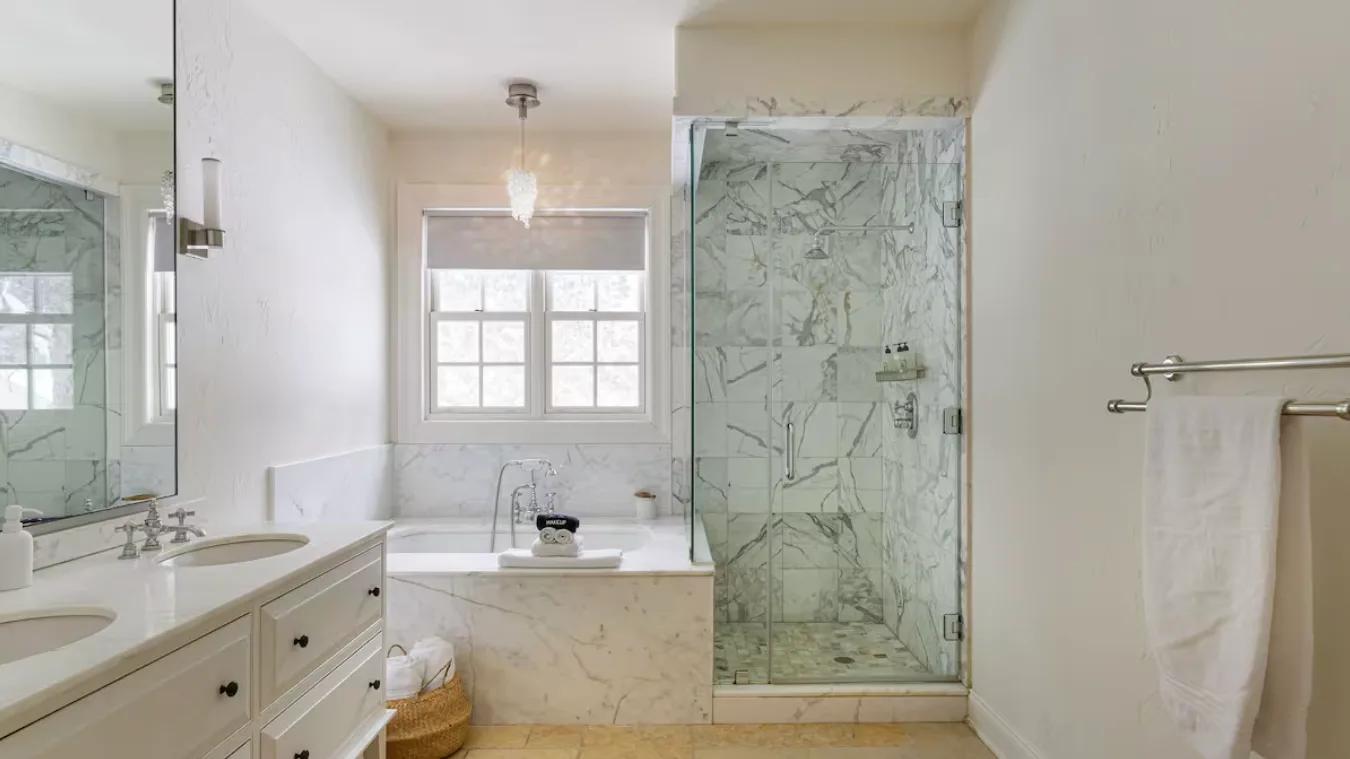 A bright bathroom with a vanity, bathtub, and glass shower.