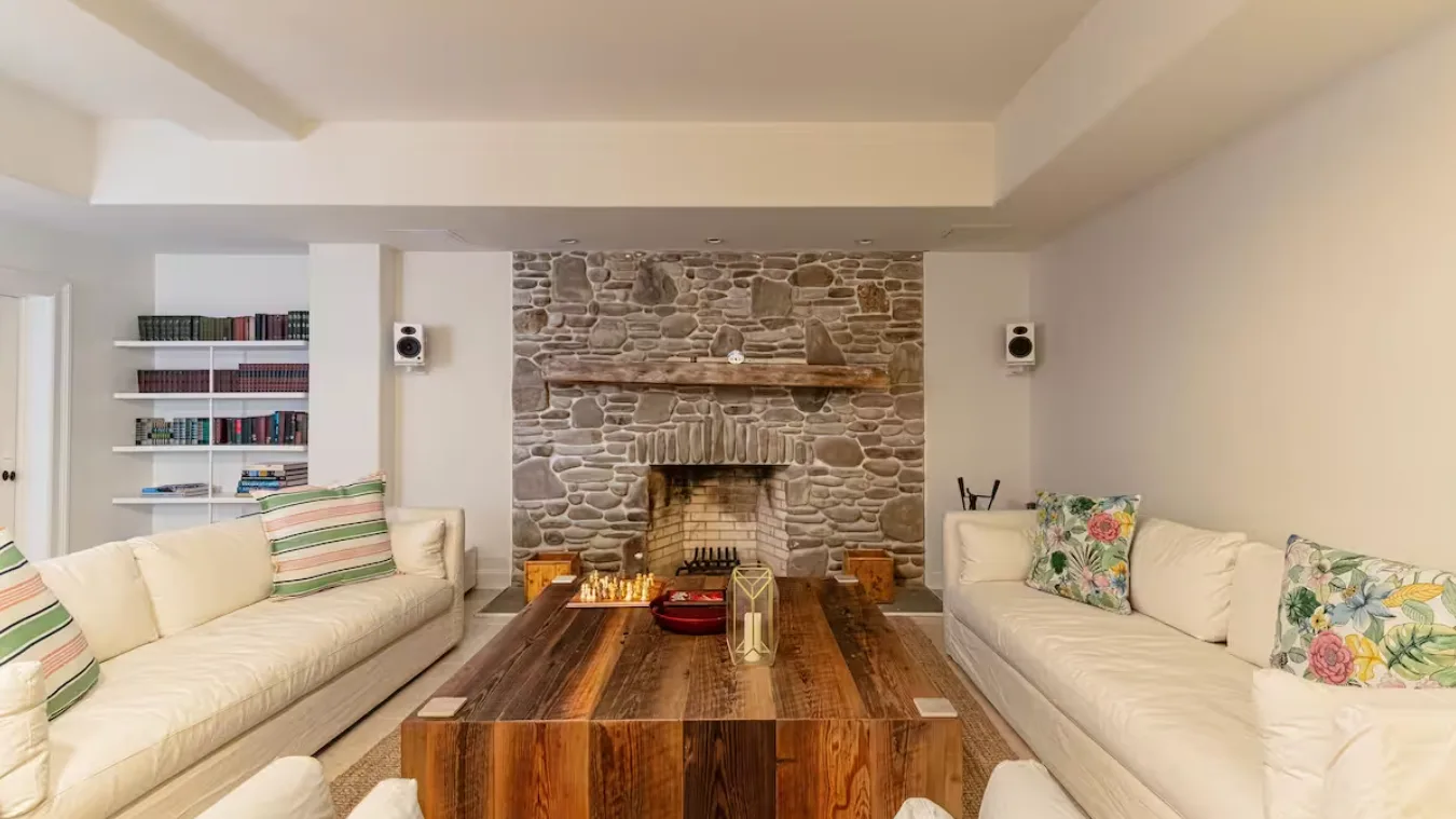 A living room with seating arranged around a stone fireplace and wooden coffee table.