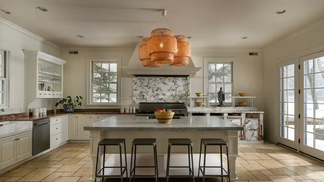 A bright kitchen with a central island, countertop seating, and large windows.
