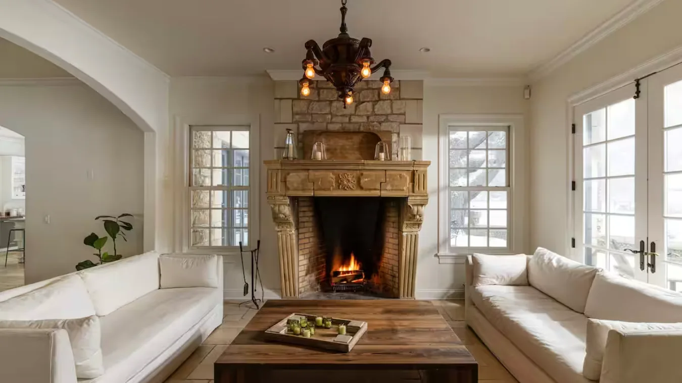 A living room with seating around a stone fireplace and glass doors.