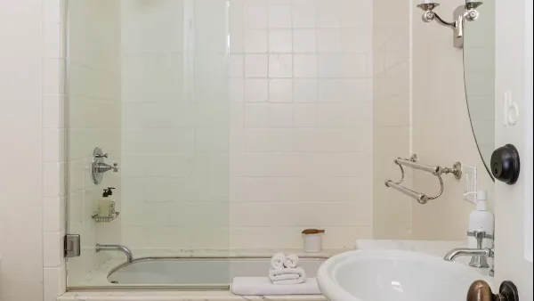 A tiled bathroom with a bathtub, sink, and folded towels.
