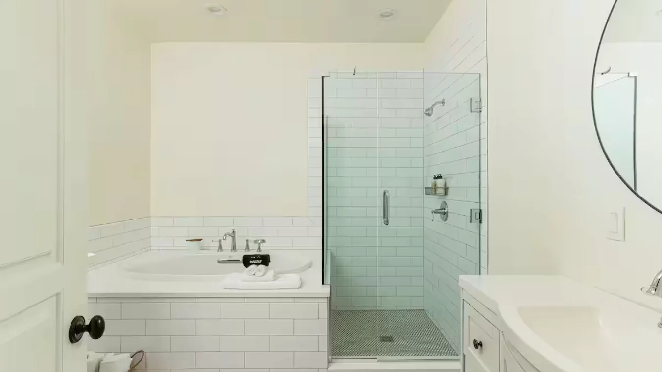 A bright bathroom with a tiled shower and a bathtub beside a vanity.