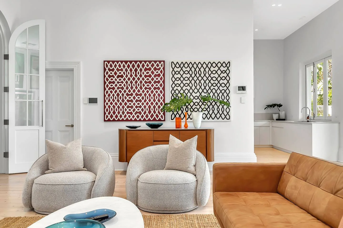A bright living room with upholstered seating and abstract artwork above a wooden console.