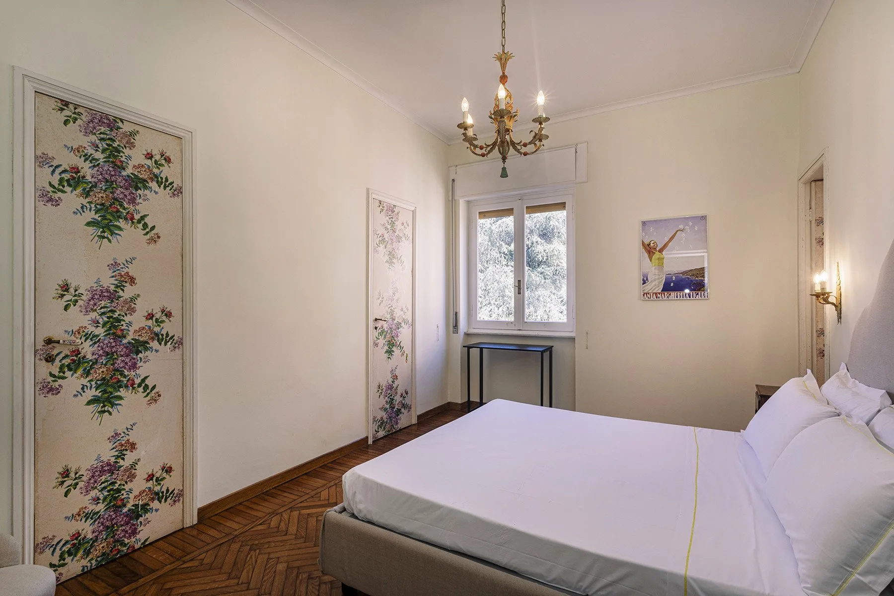 Un dormitorio con una cama tendida, paneles florales y una ventana.