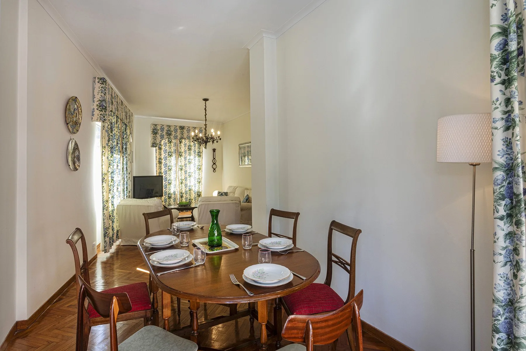 Comedor con una mesa de madera y sillas junto a cortinas florales.