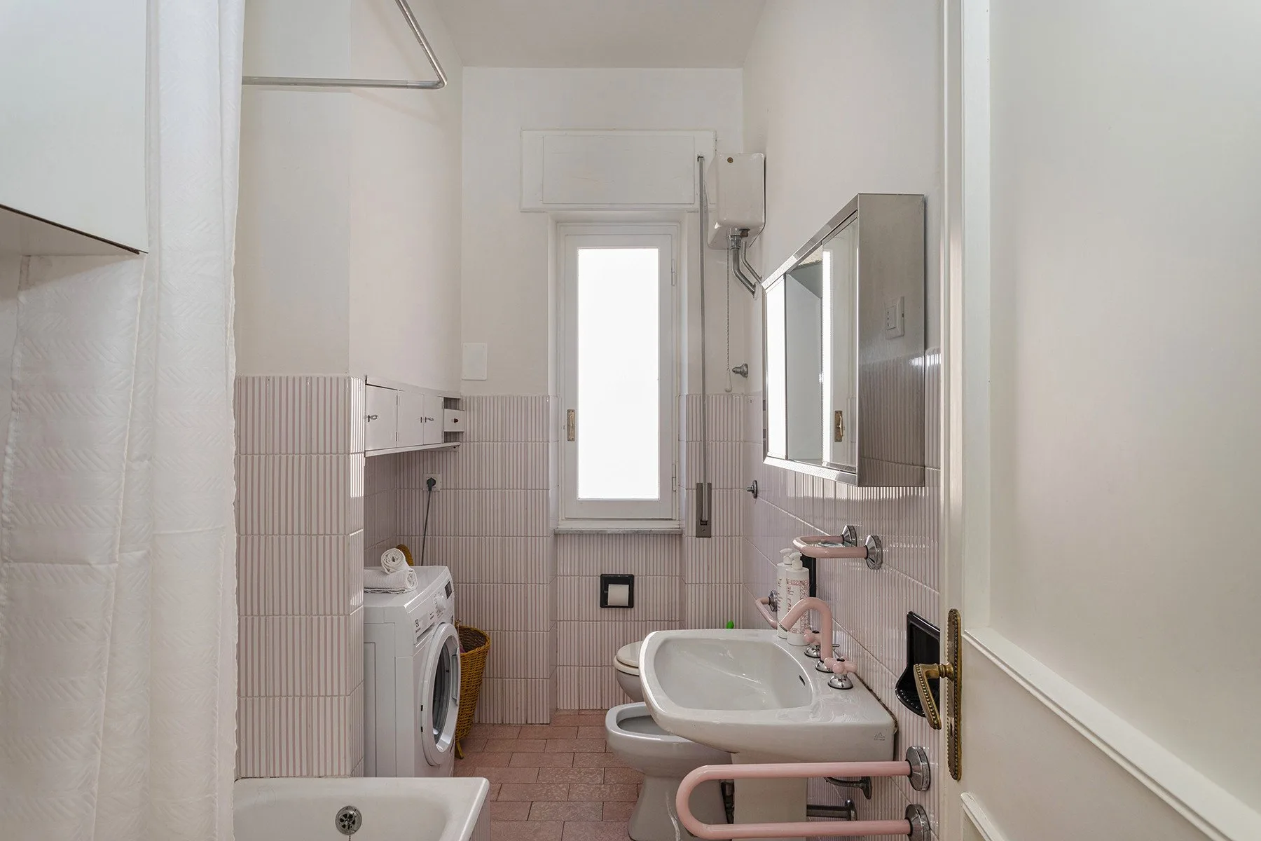 Un baño con azulejos, lavabo, inodoro y lavadora.