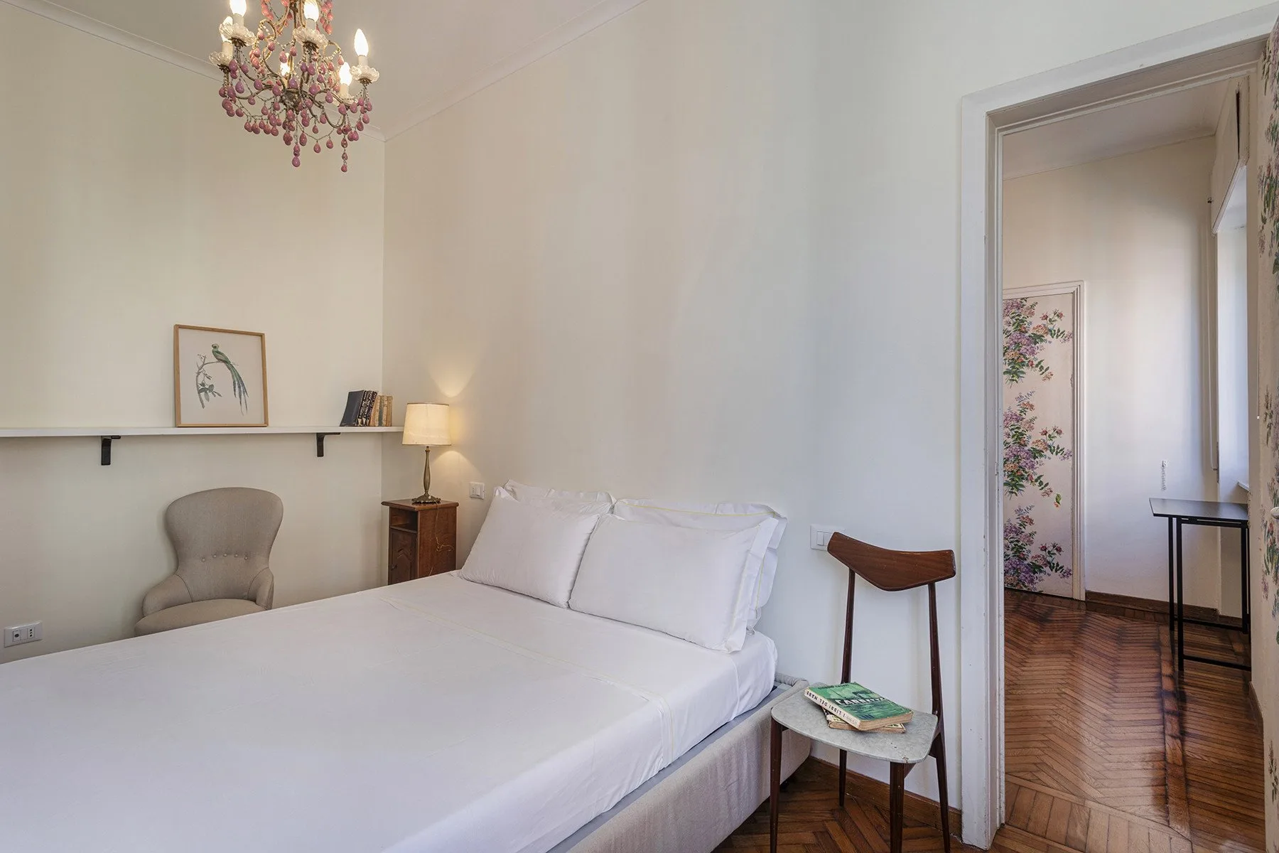 Un dormitorio luminoso con una cama hecha y una puerta al pasillo.
