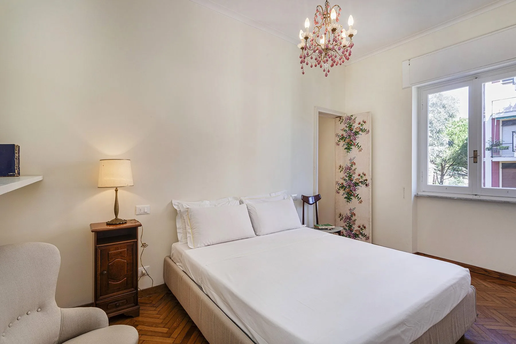 Un dormitorio luminoso con una cama bien hecha y una ventana grande.