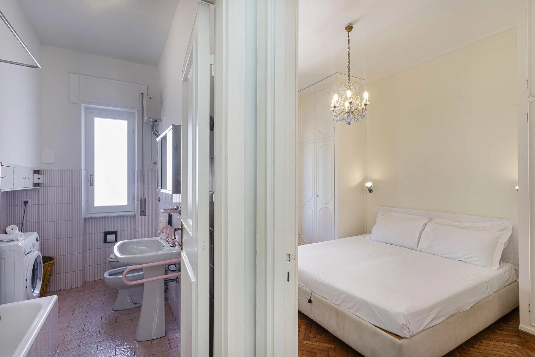 Dormitorio con una cama blanca, visto junto a un baño contiguo.