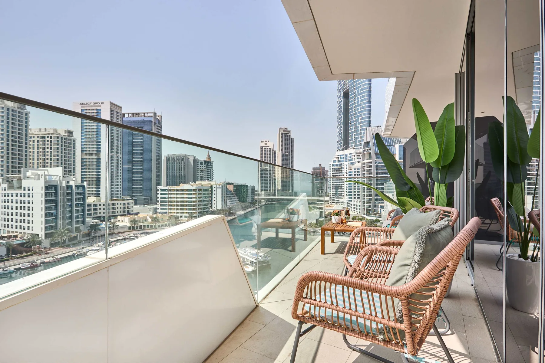 A balcony with woven seating overlooks a city skyline.