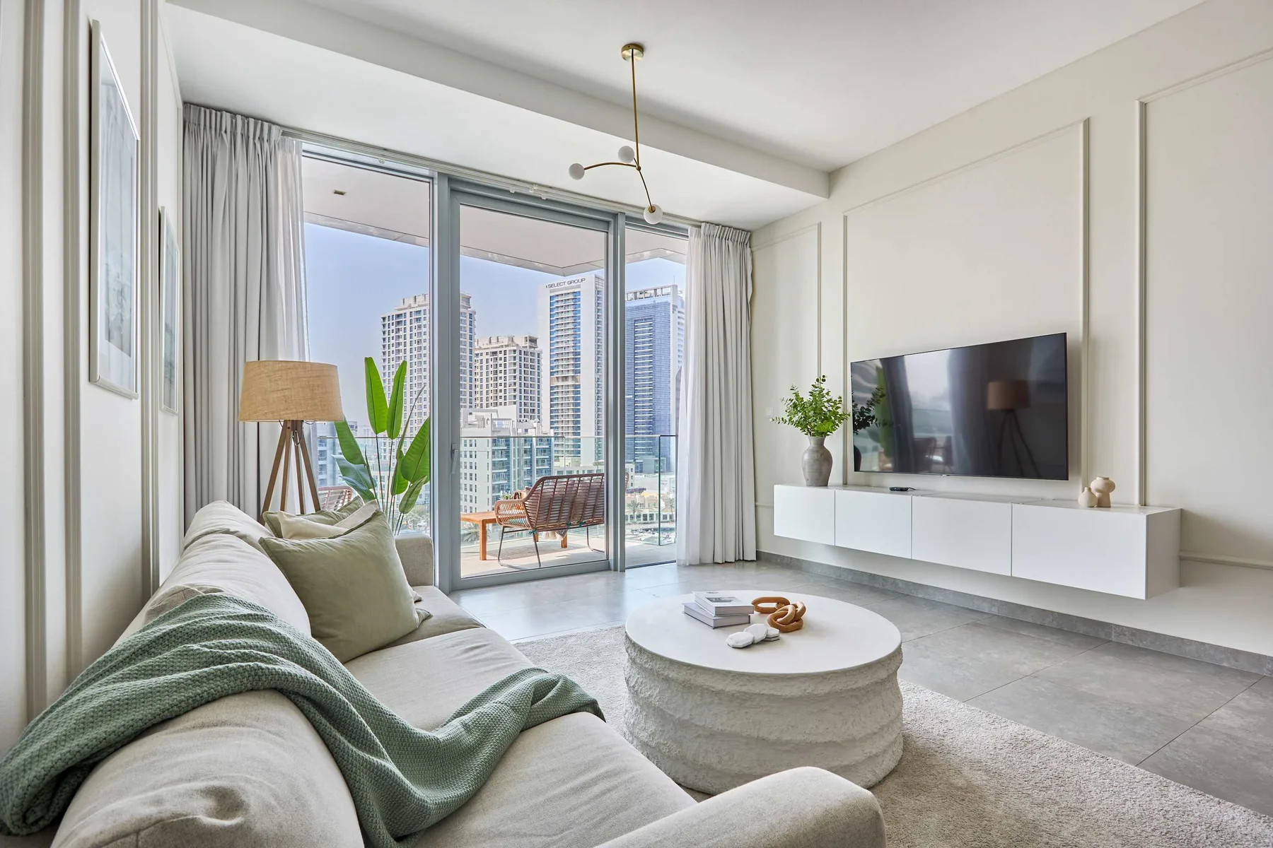 Una sala luminosa con asientos, un televisor y grandes puertas de vidrio con vistas a la ciudad.