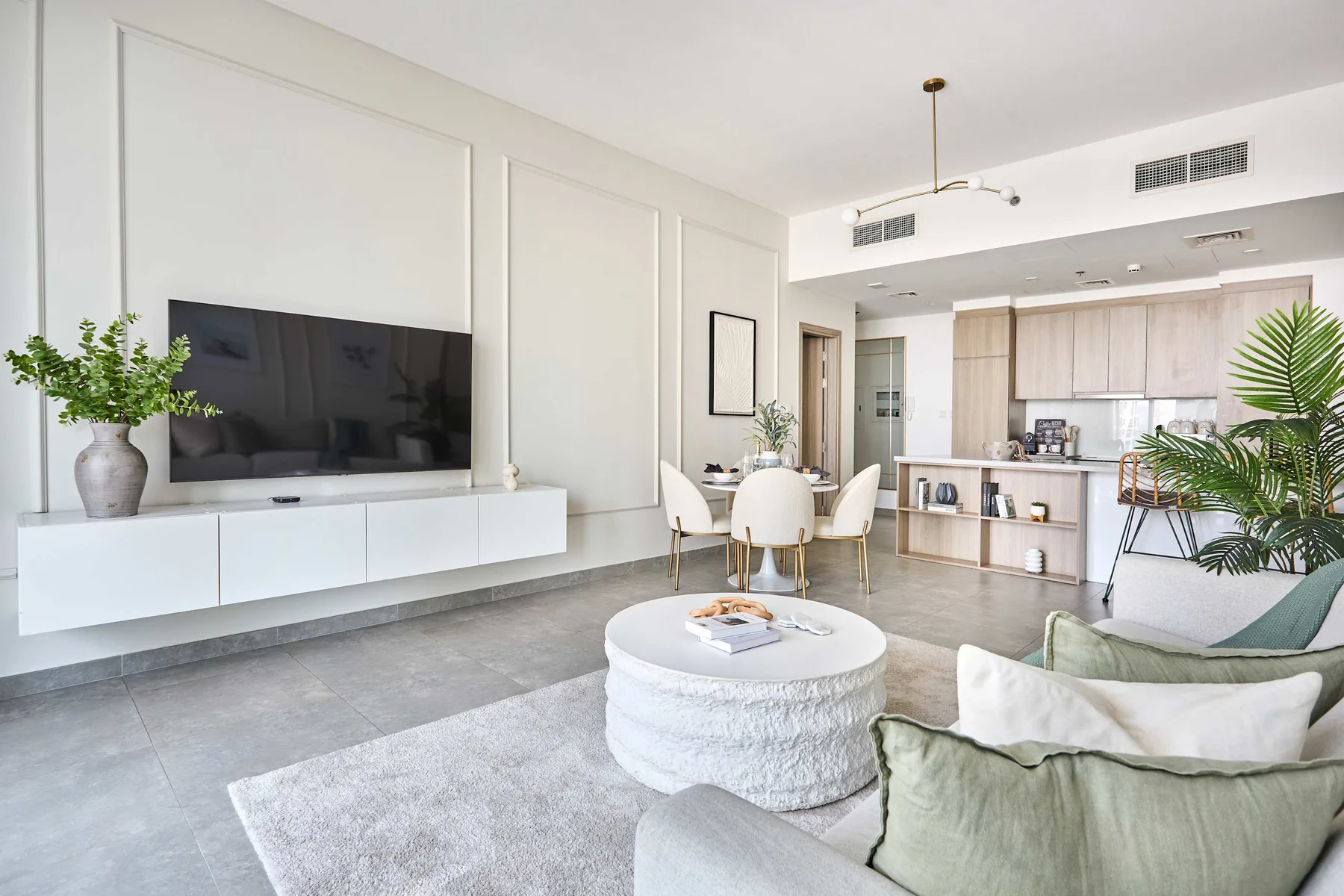 Una luminosa sala de estar diáfana con televisión, asientos y cocina.
