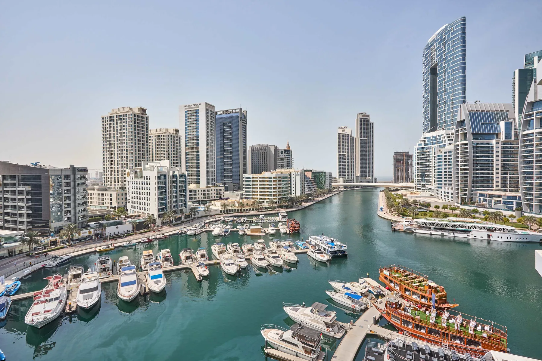 A marina with boats sits among modern high-rise buildings along a waterfront.