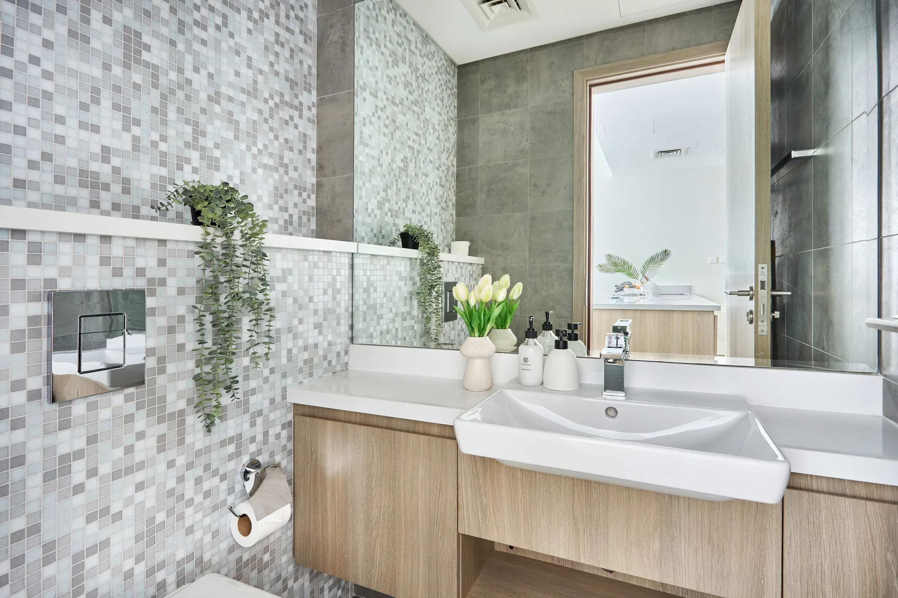 A modern bathroom vanity with a white sink, tiled walls, and a large mirror.