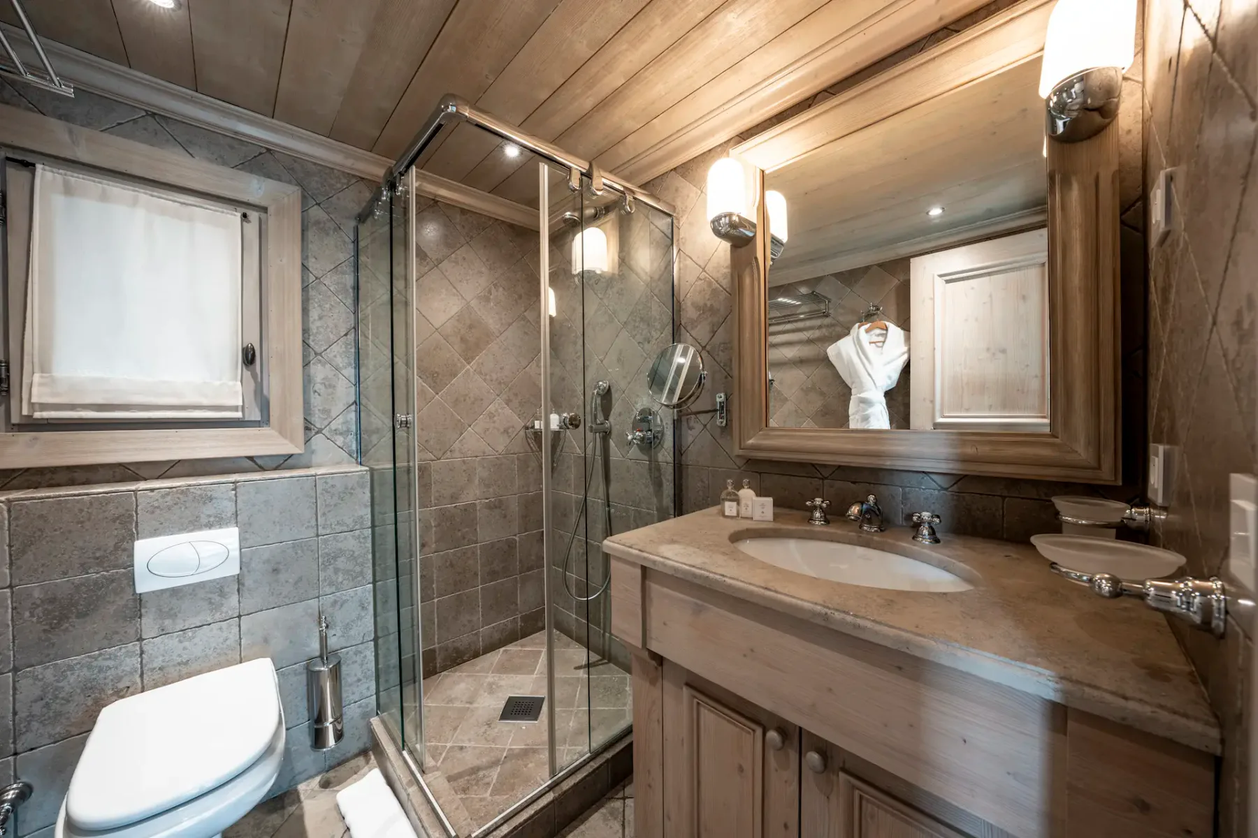 Rustic bathroom with wooden accents, a glass-enclosed shower, a sink with a large mirror, and a towel on the counter.