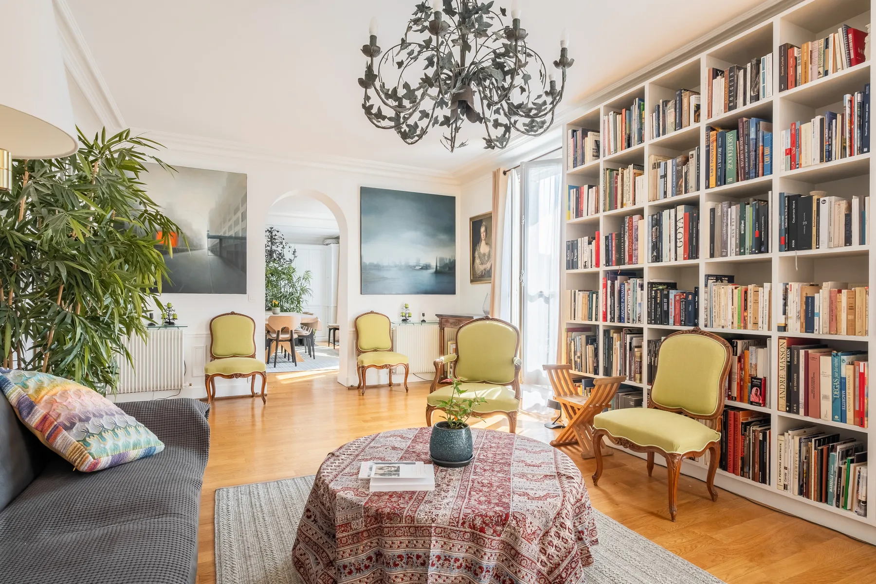 A bright living room with a large bookcase and seating around a coffee table.
