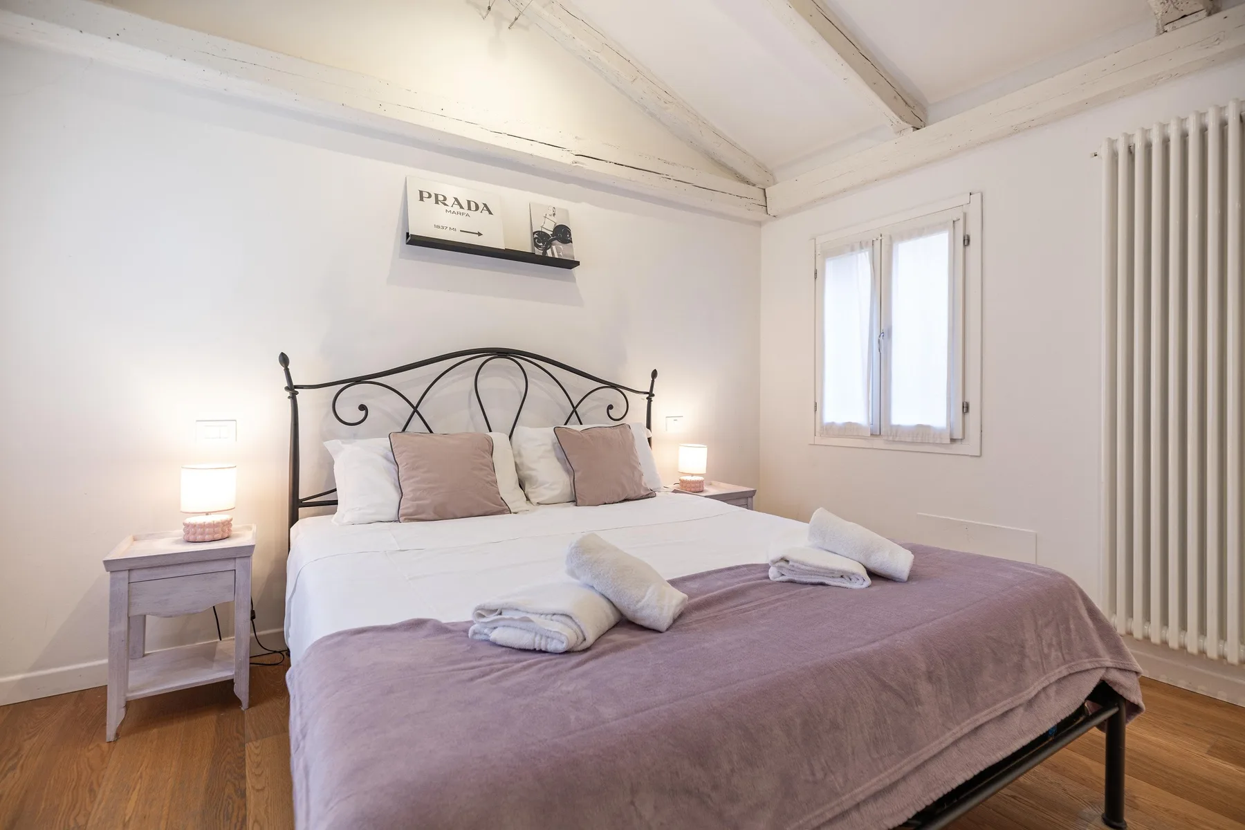 Un dormitorio luminoso con una cama doble, mesitas de noche y una ventana.