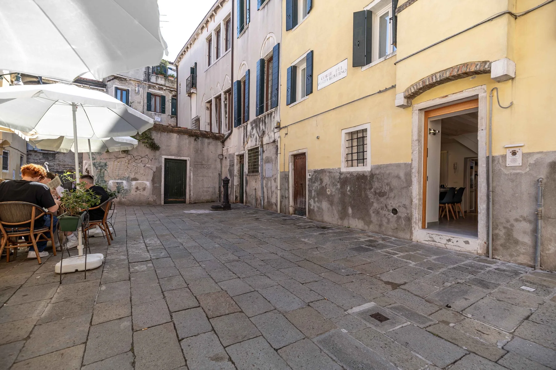 Un patio pavimentado con asientos al aire libre y sombrillas junto a varios edificios.