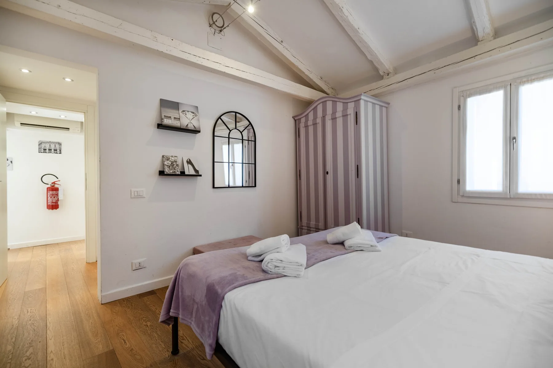 Un dormitorio con una cama, un armario y una ventana.
