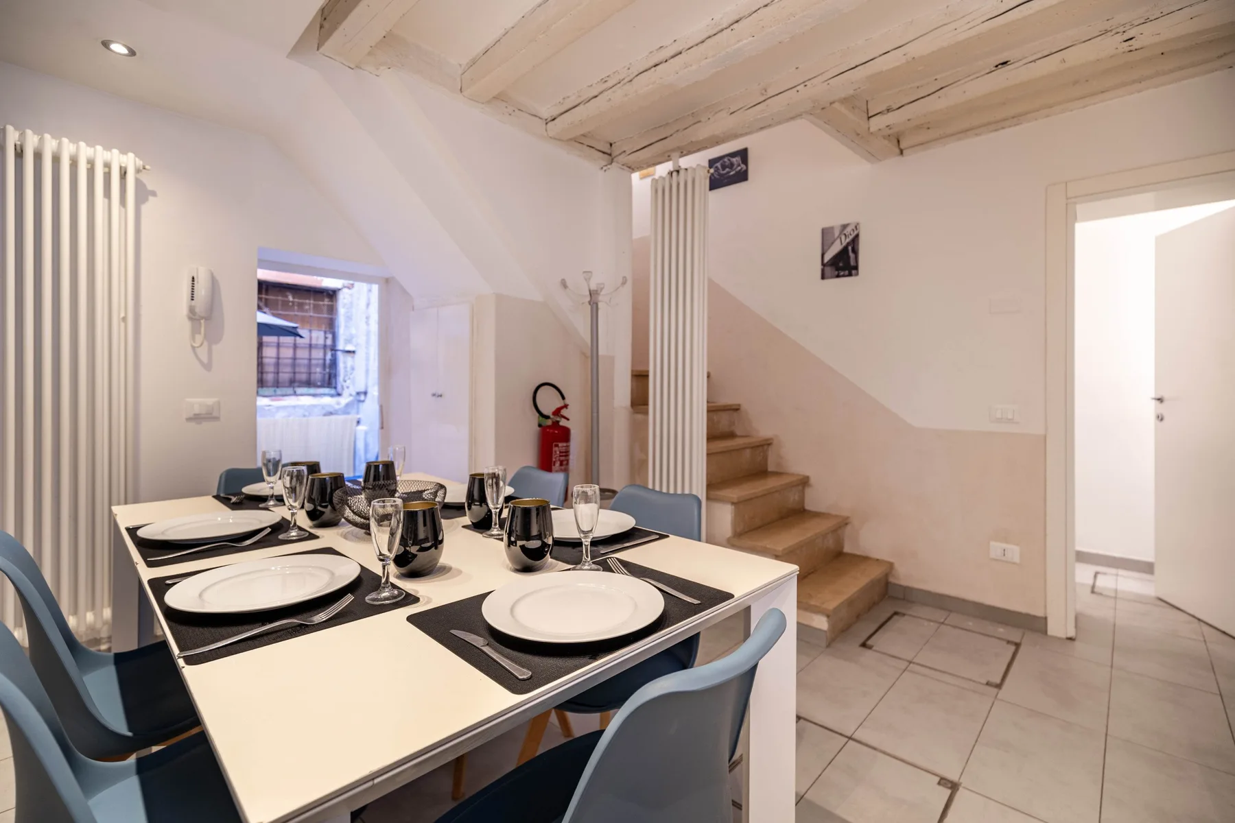 Un comedor con una mesa puesta con platos y sillas junto a una escalera.