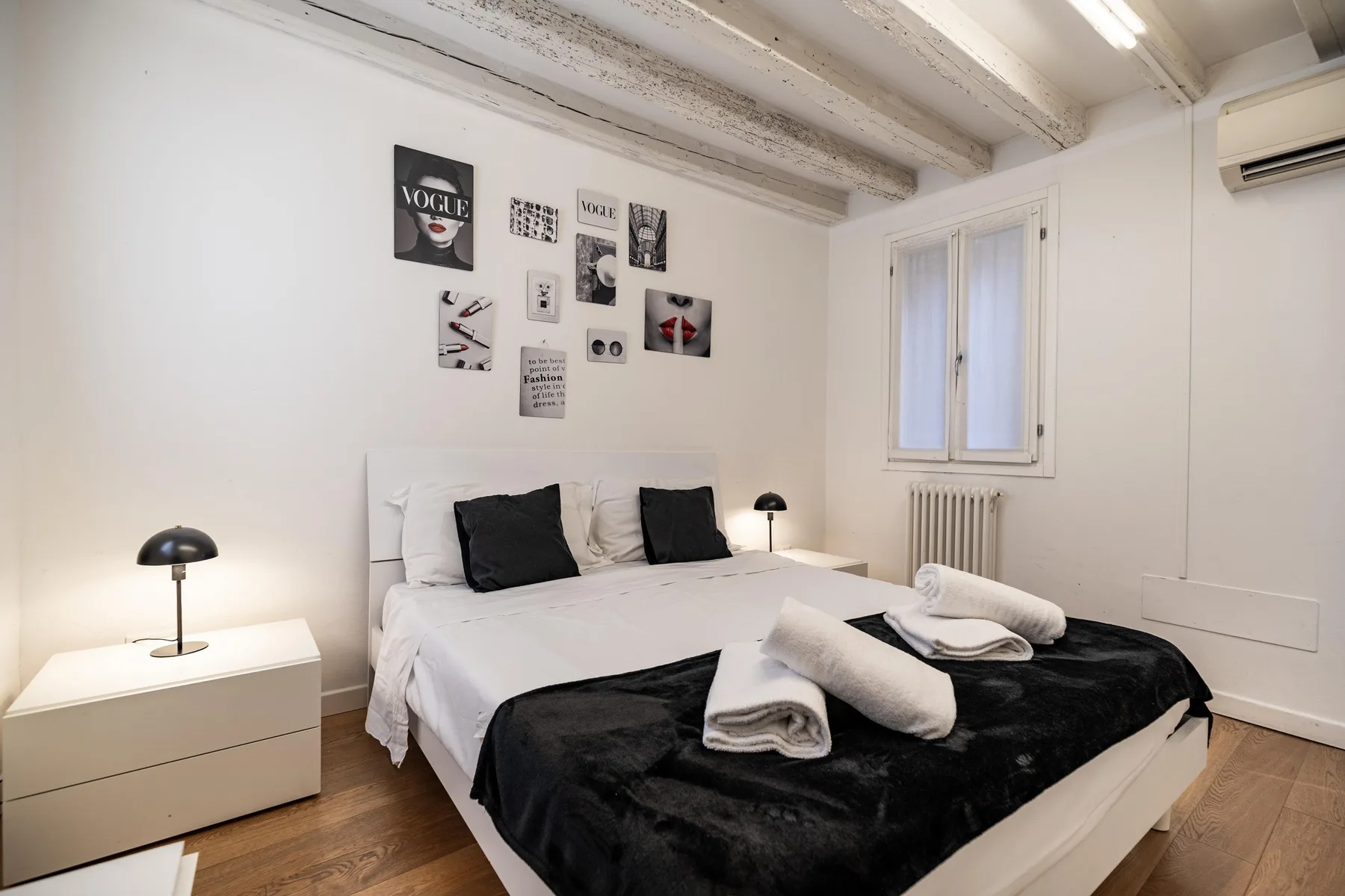 Un dormitorio luminoso con una cama, cuadros en la pared y una ventana.