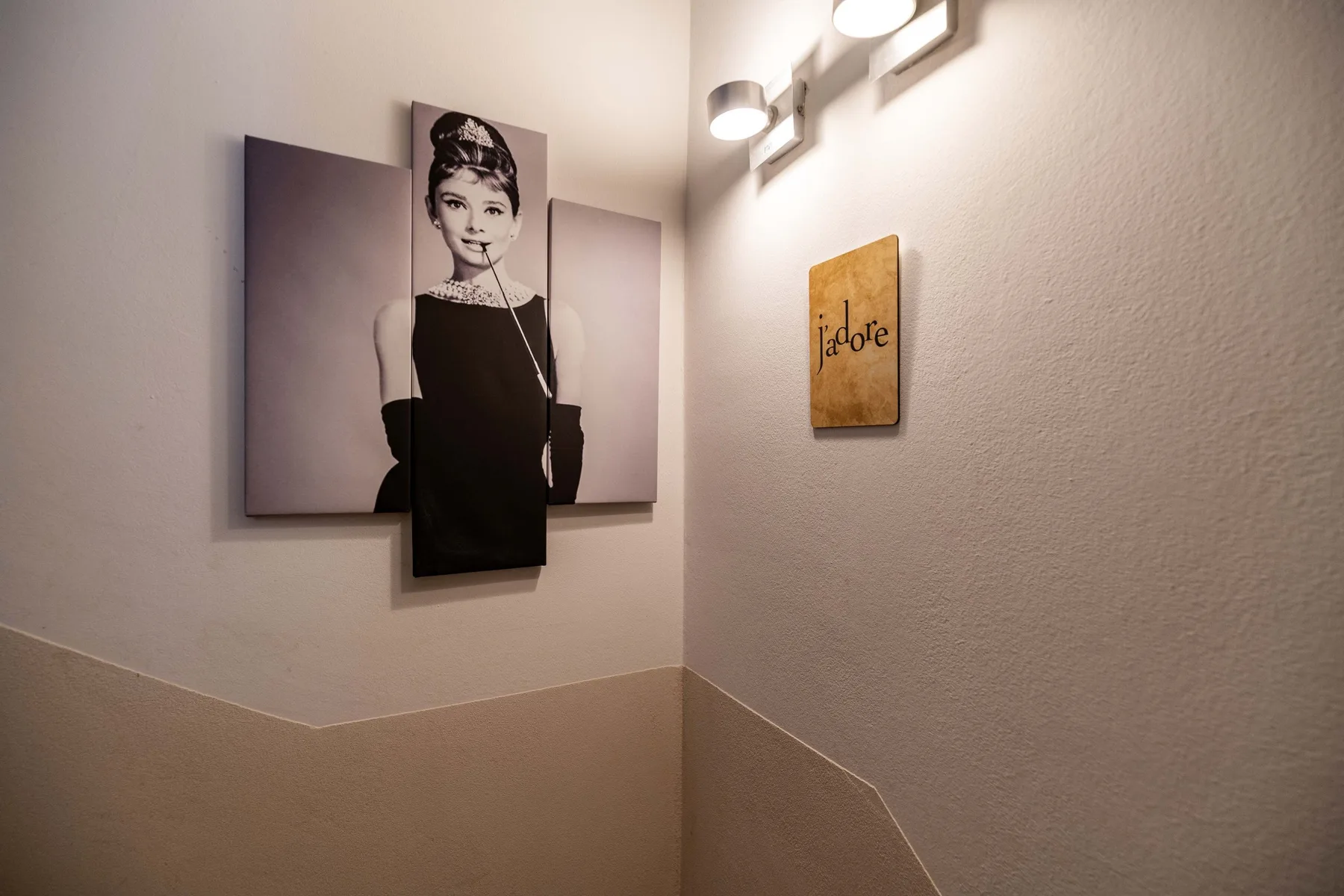Una pared de escalera muestra un retrato y un pequeño letrero decorativo.