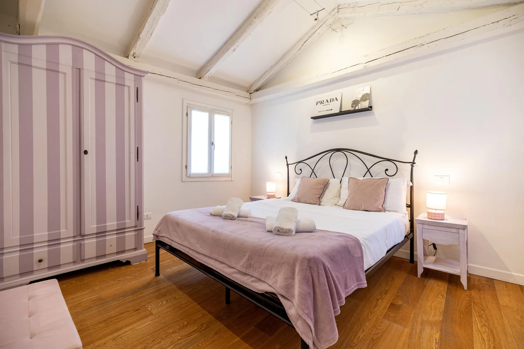 Un dormitorio con una cama doble, un armario a rayas y suelo de madera.