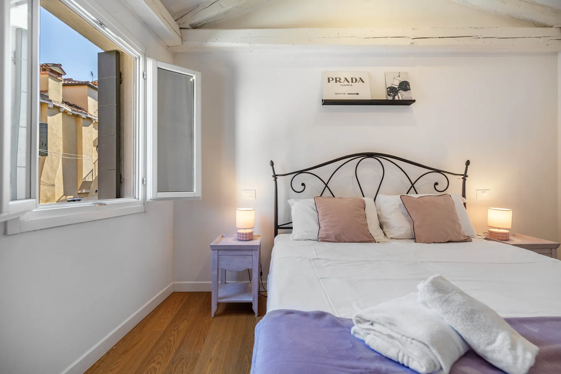 Un dormitorio con una cama doble, mesitas de noche y una ventana abierta.
