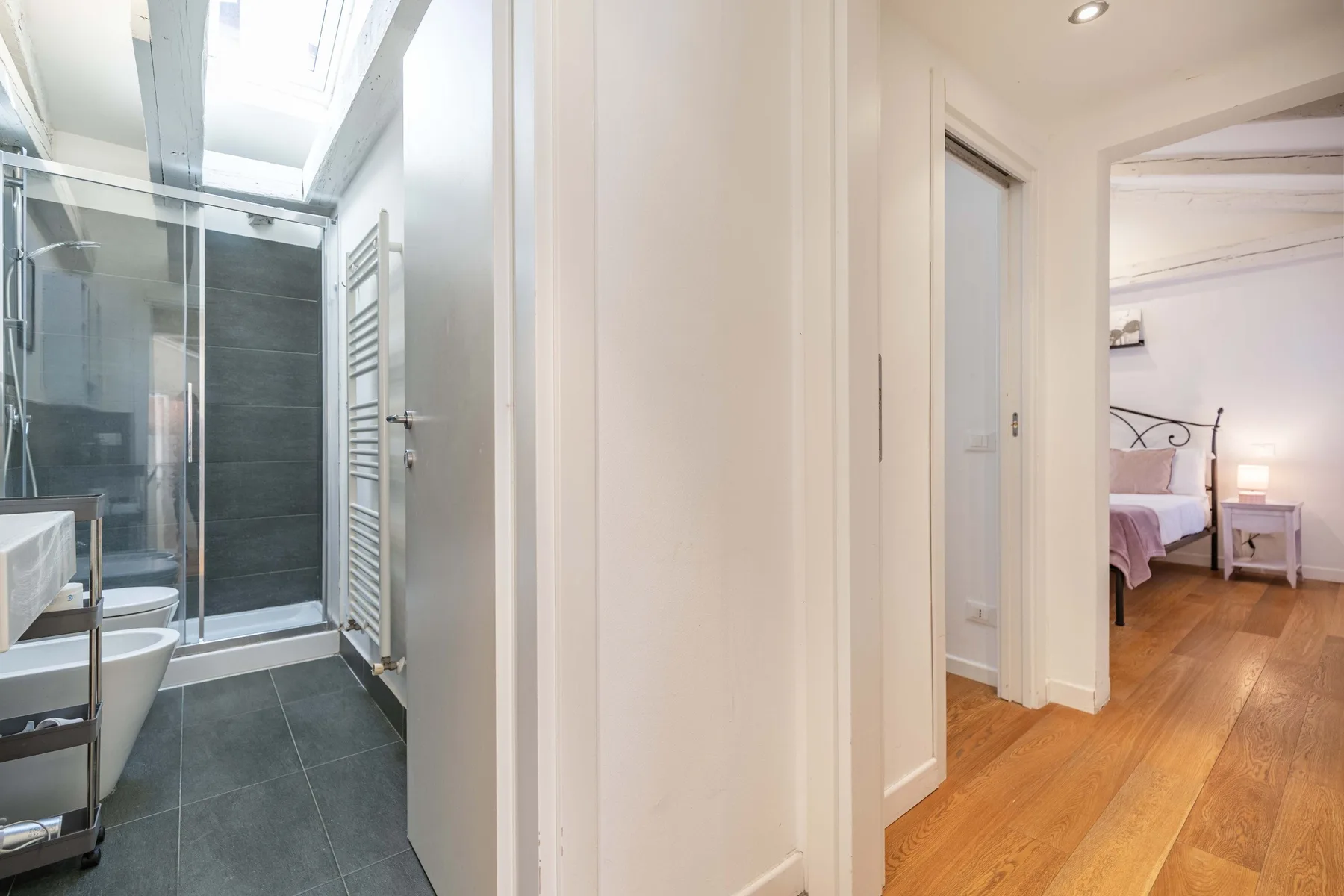Un baño da a un pasillo que conduce a un dormitorio.