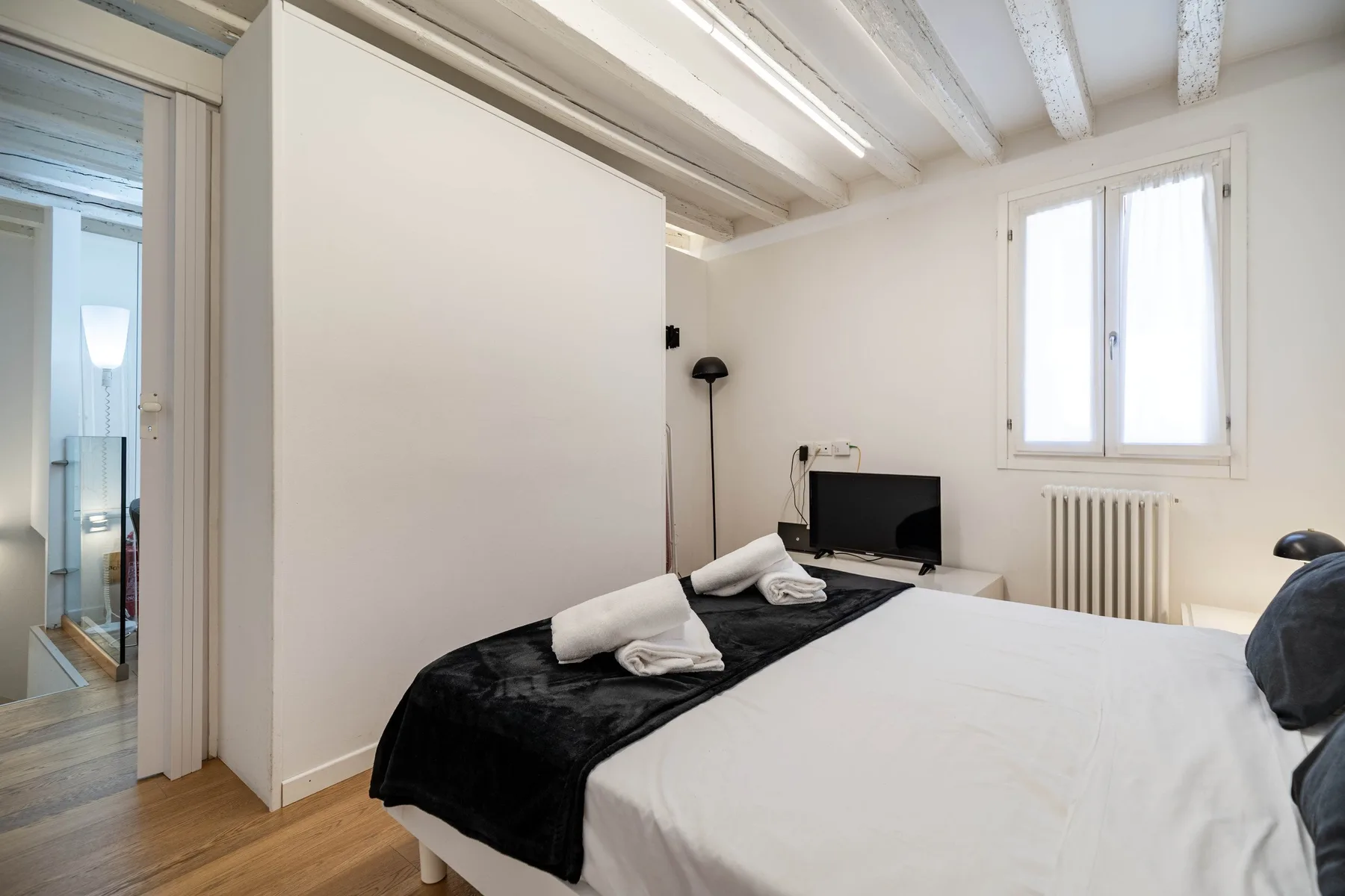 Un dormitorio con una cama, un televisor y una ventana.