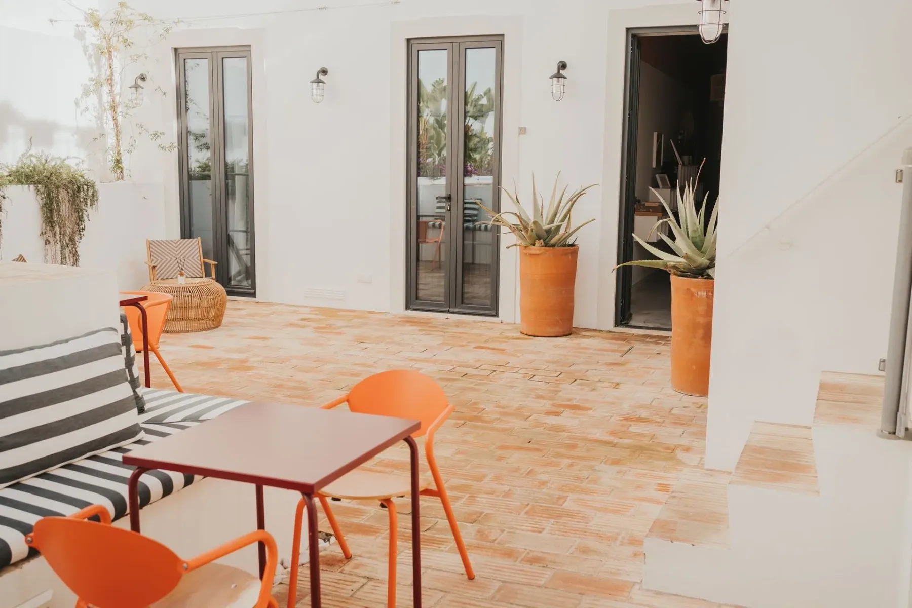 Zona de estar en el patio con una mesa y un sofá de rayas.