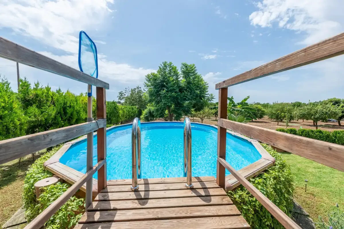 Una piscina al aire libre con una plataforma de madera y vegetación alrededor.
