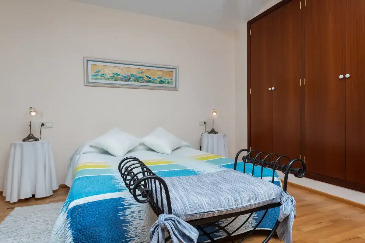 Un dormitorio con una cama bien hecha y un armario de madera.