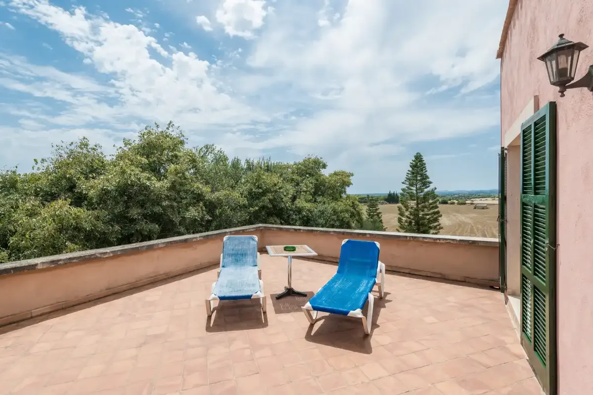 Una terraza en la azotea con asientos al aire libre da a árboles y campo abierto.