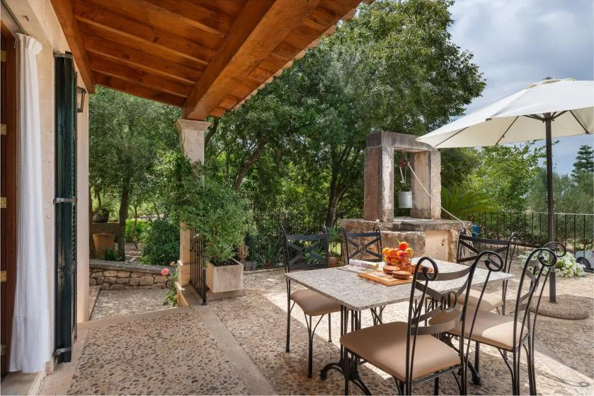 Un patio comedor cubierto con una mesa, asientos y una sombrilla grande.