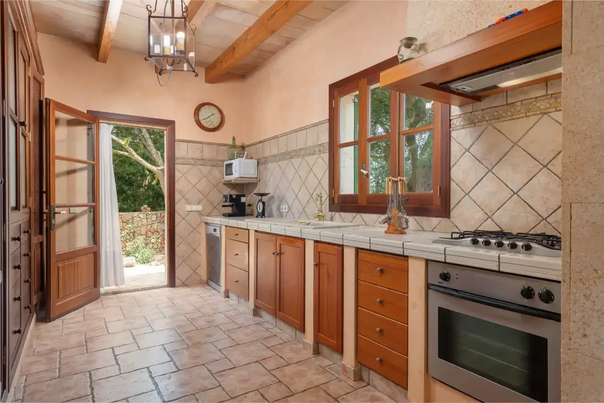 Una cocina rústica con armarios de madera, azulejos en la pared y una ventana con vistas a la vegetación.