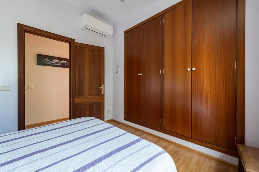 Un dormitorio con una cama a rayas y grandes armarios de madera.