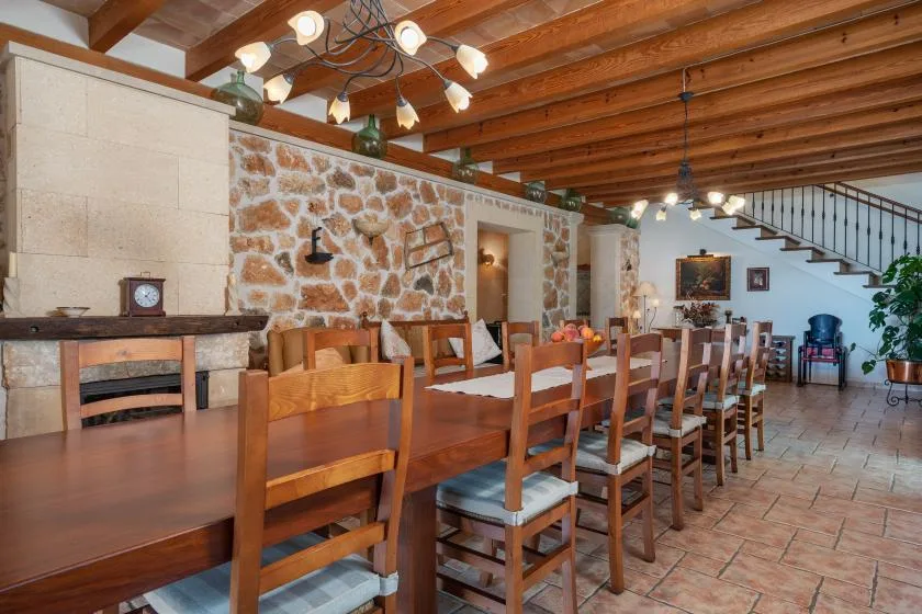 Comedor con una mesa larga de madera, sillas y una pared de piedra.